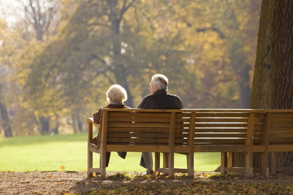 Older couple sitting on a bench in a park