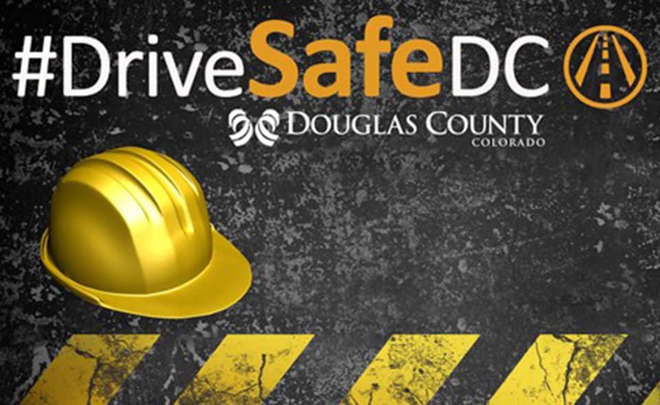Drive Safe text on asphalt road with hard hat and caution lines