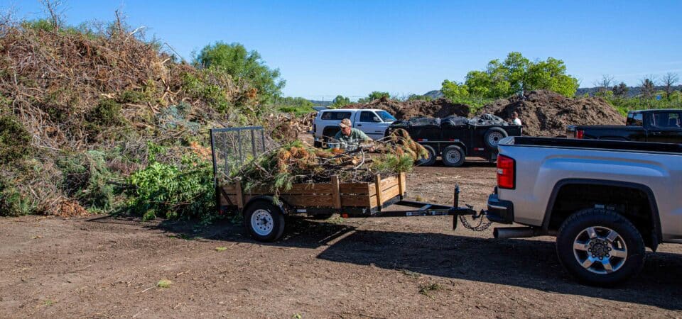 trucking backing up trailer with branches at slash mulch site