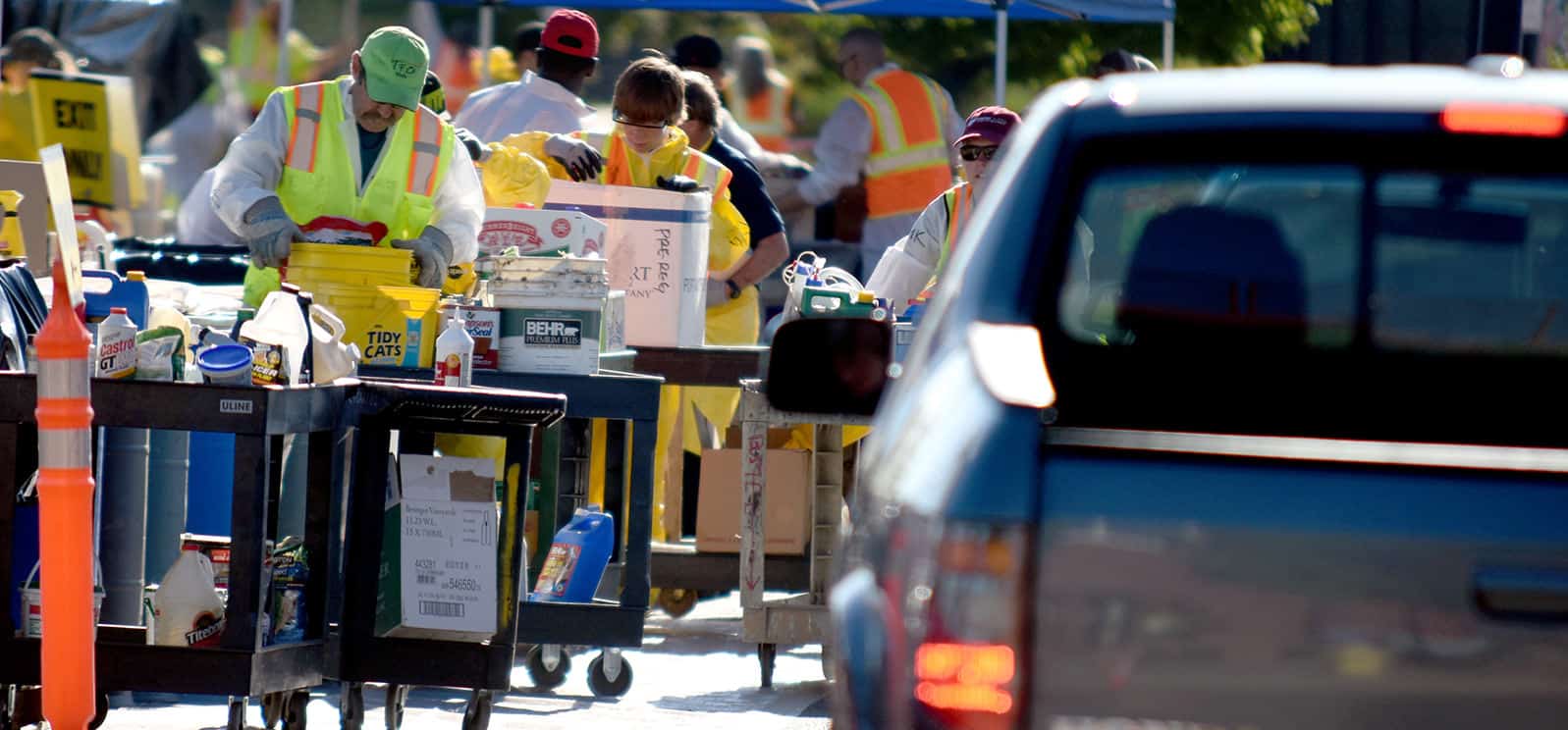Cars driving through household chemical waste roundup with volunteers